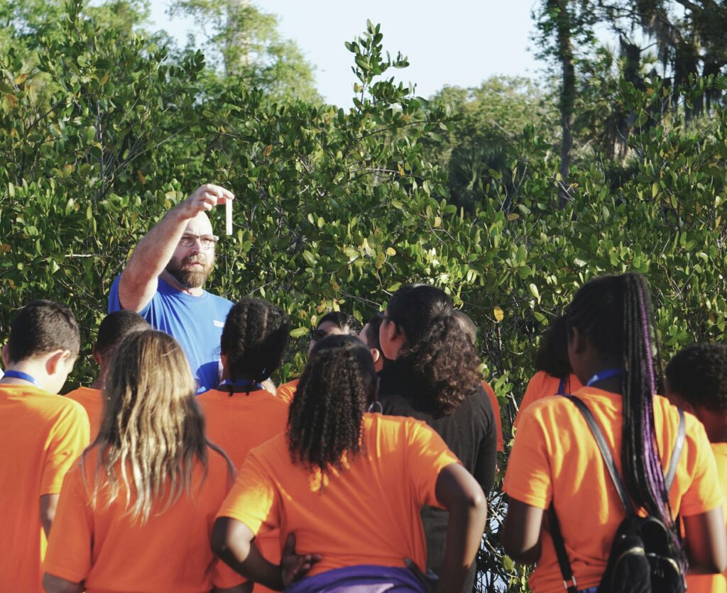 Students learning outdoors from a teacher. 